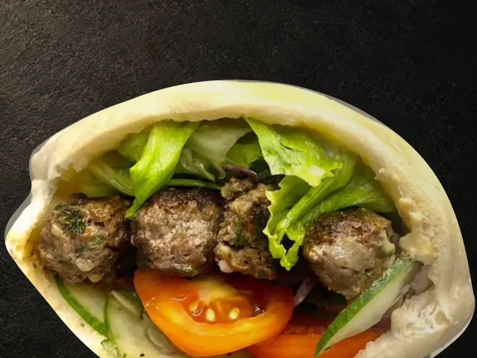 A beef kebab pita sandwich with lettuce, tomato and cucumber